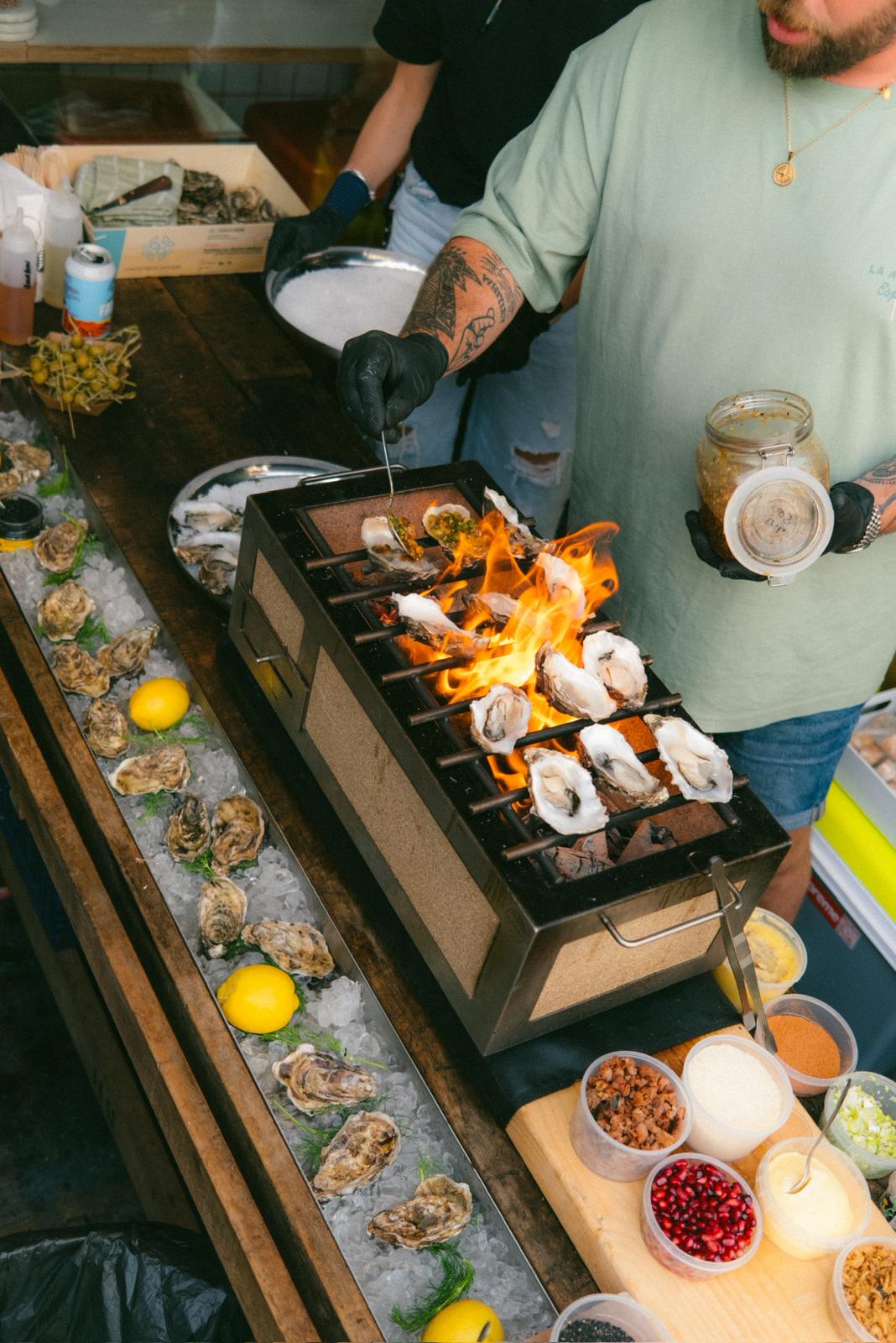 Oysters cooking over open flames on the trailer grill