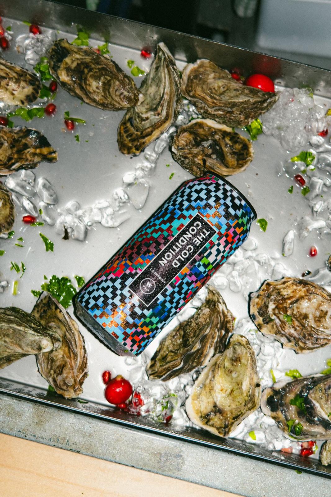 Oysters arranged on ice in a tray with herbs and pomegranate