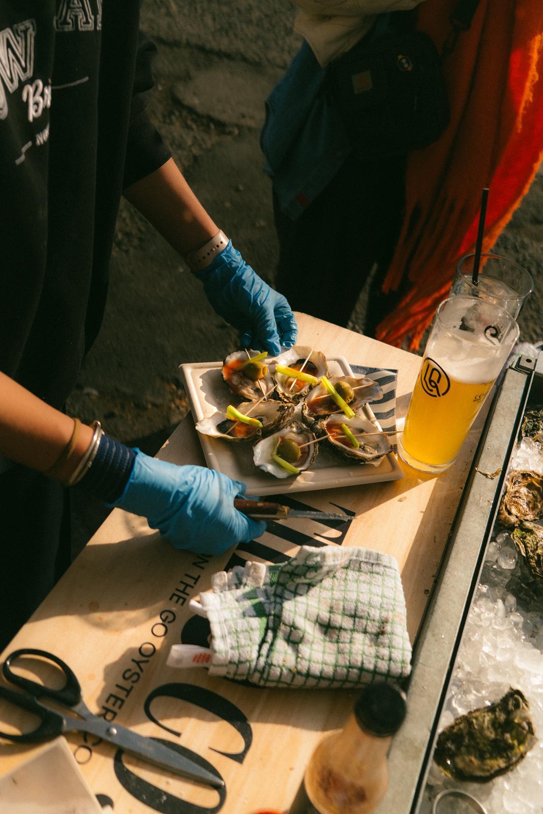 A platter of cooked oysters being served with a beer